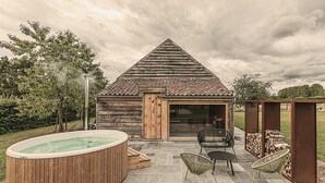 A wooden cabin with a sloped roof, a hot tub, and outdoor seating.