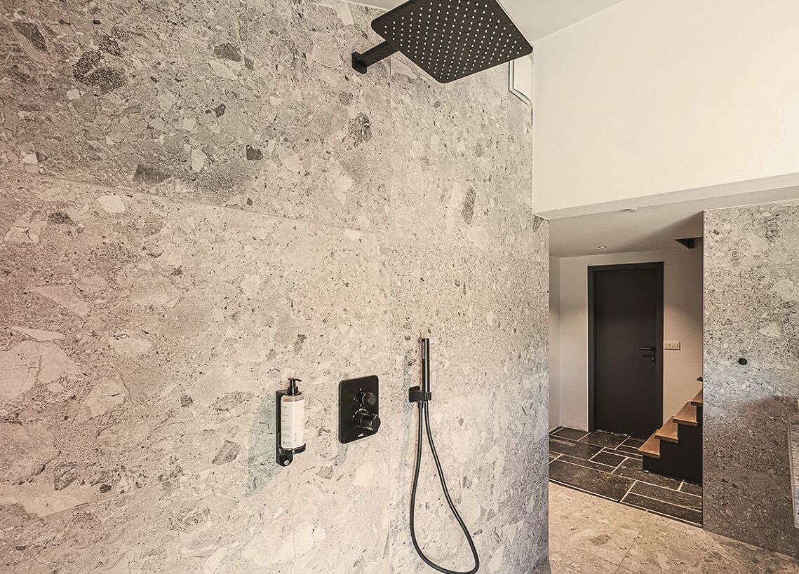 Un bany modern amb una paret de pedra, un vàter de dutxa i un panell de control.