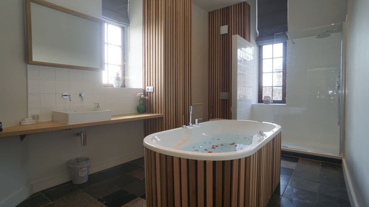 Ein modernes Badezimmer mit einer frei stehenden Badewanne, einem großen Spiegel und einer Duschkabine.