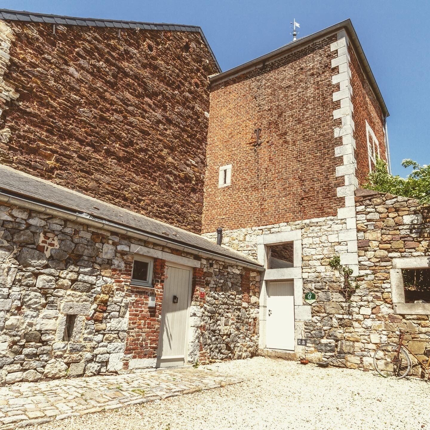 Un edificio de piedra con una puerta blanca y una ventana pequeña.