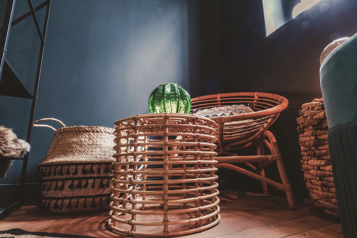 Des paniers en osier et un objet en verre vert sur un plancher en bois.