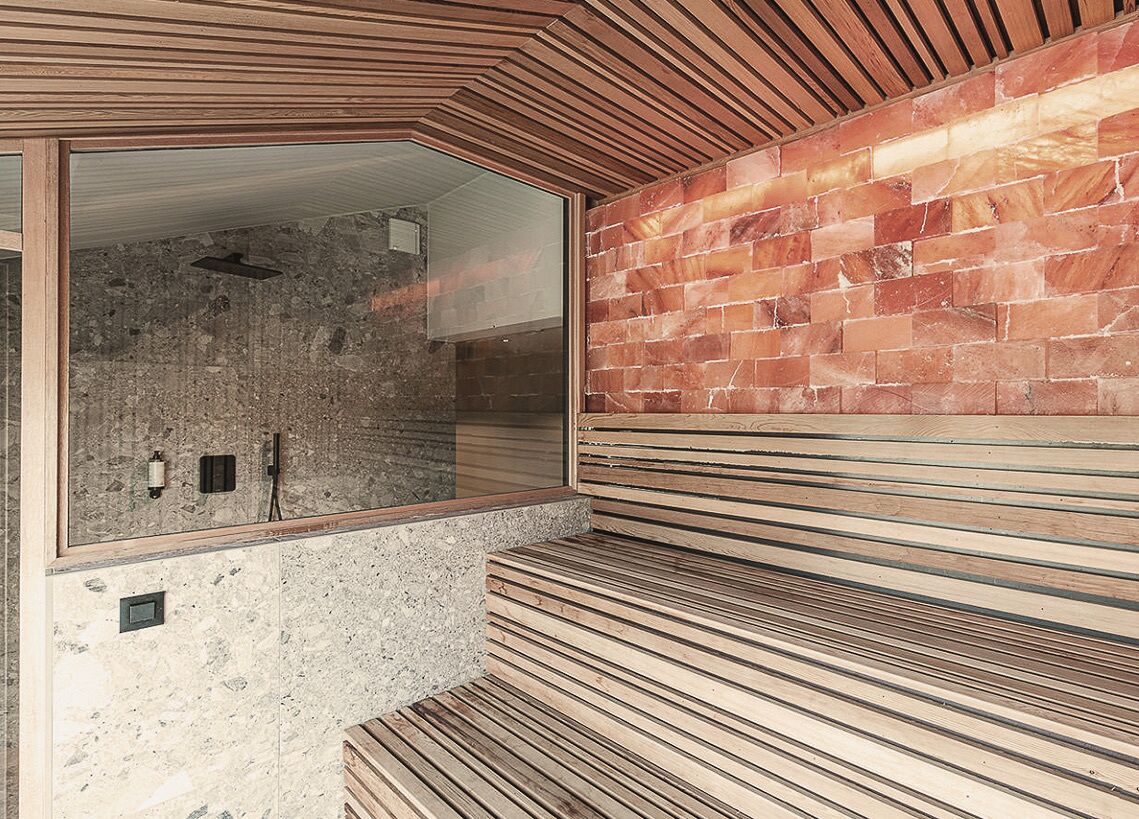 A modern bathroom with a stone wall, wooden slats, and a large mirror.