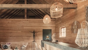 A rustic wooden interior with high ceilings, wicker furniture, and hanging light fixtures.