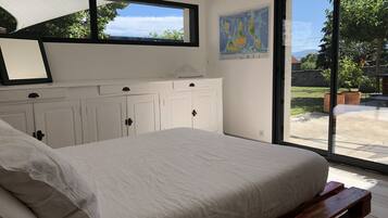 A bedroom with a large bed, white cabinets, and a window with a view of the outdoors.
