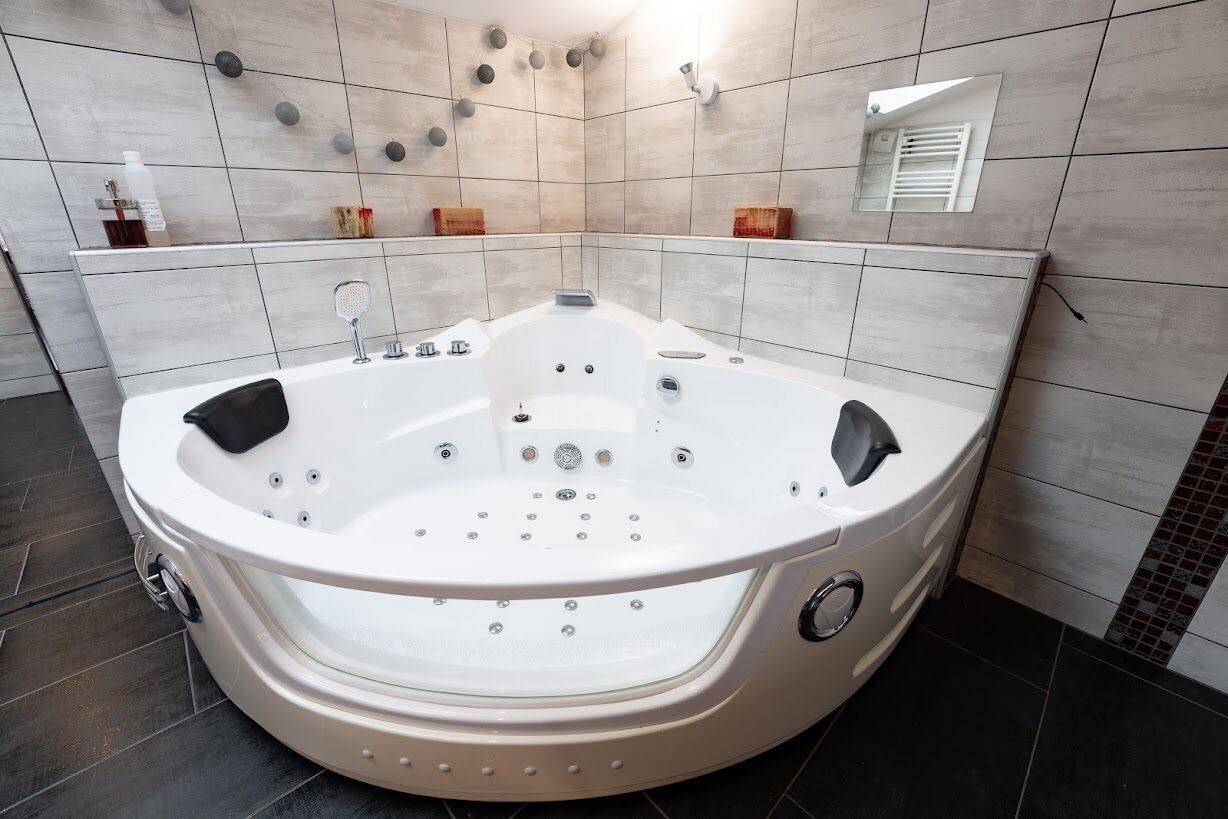 A modern bathroom with a large freestanding bathtub, tiled walls, and a small mirror.
