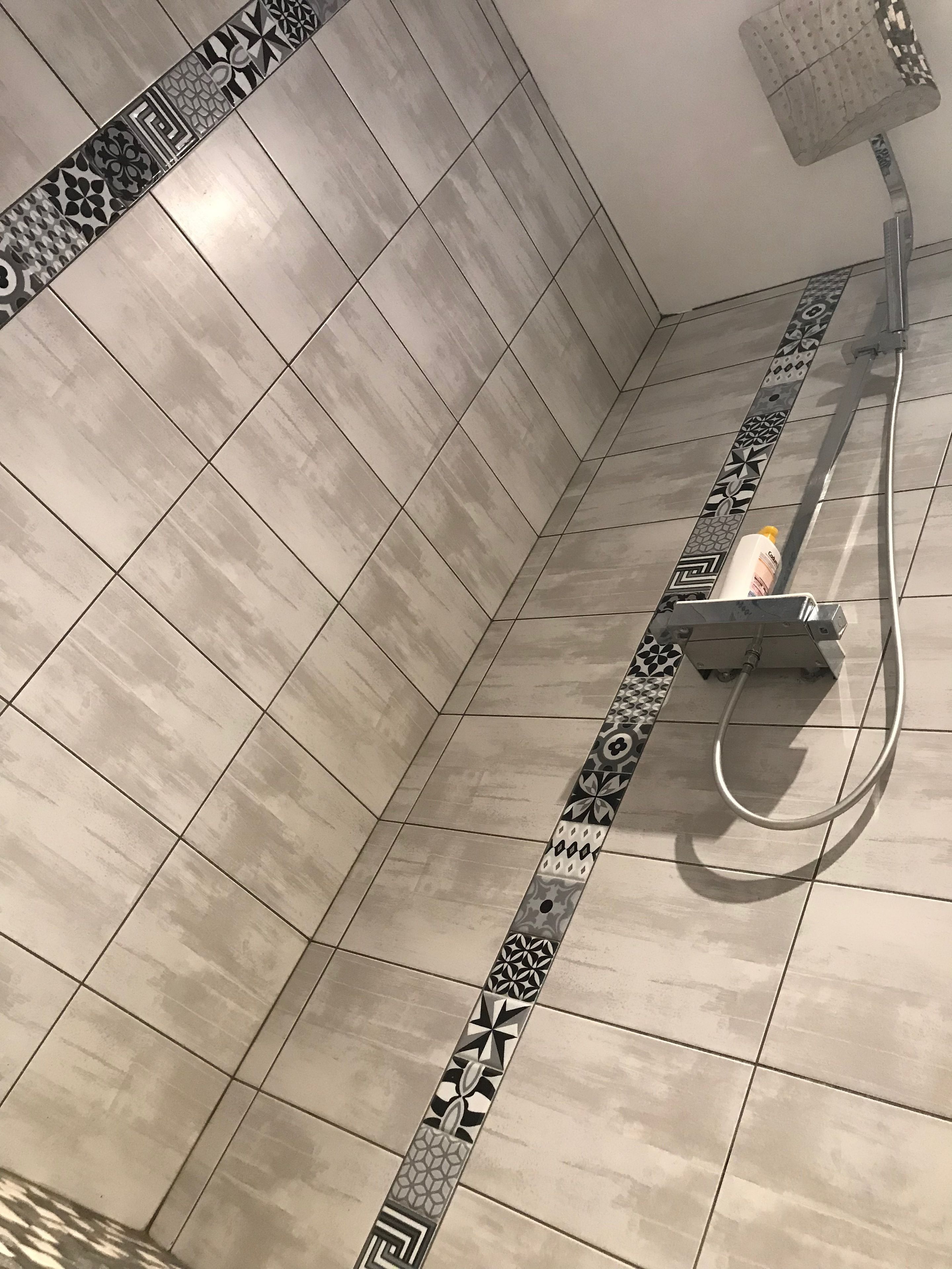 A bathroom with beige tiles and a decorative border.