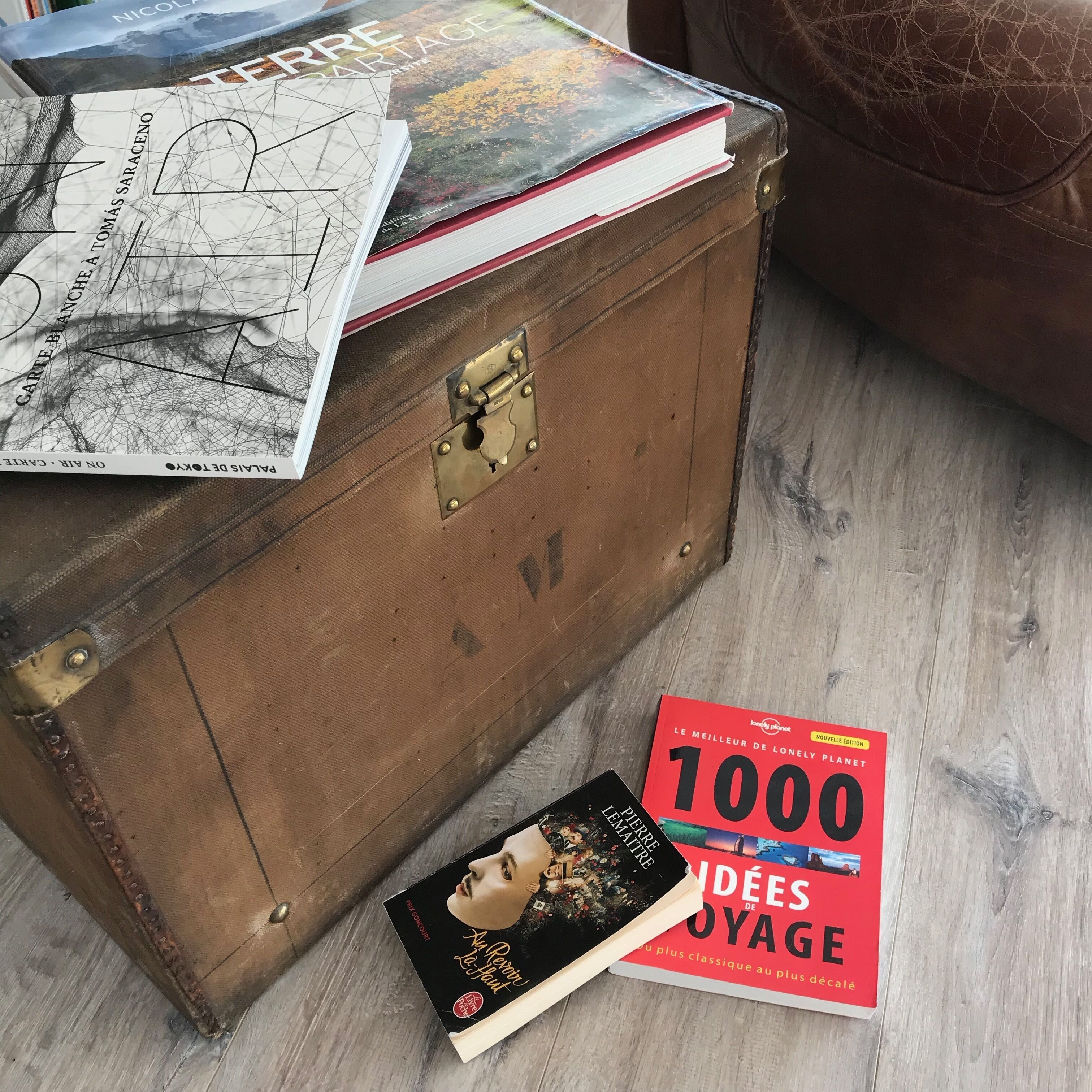 Une malle en bois sur laquelle sont posés des livres, avec deux autres livres à côté.