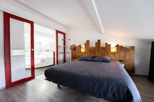 Un dormitorio con una cama grande, cabecera de madera y puerta corrediza que da al baño.