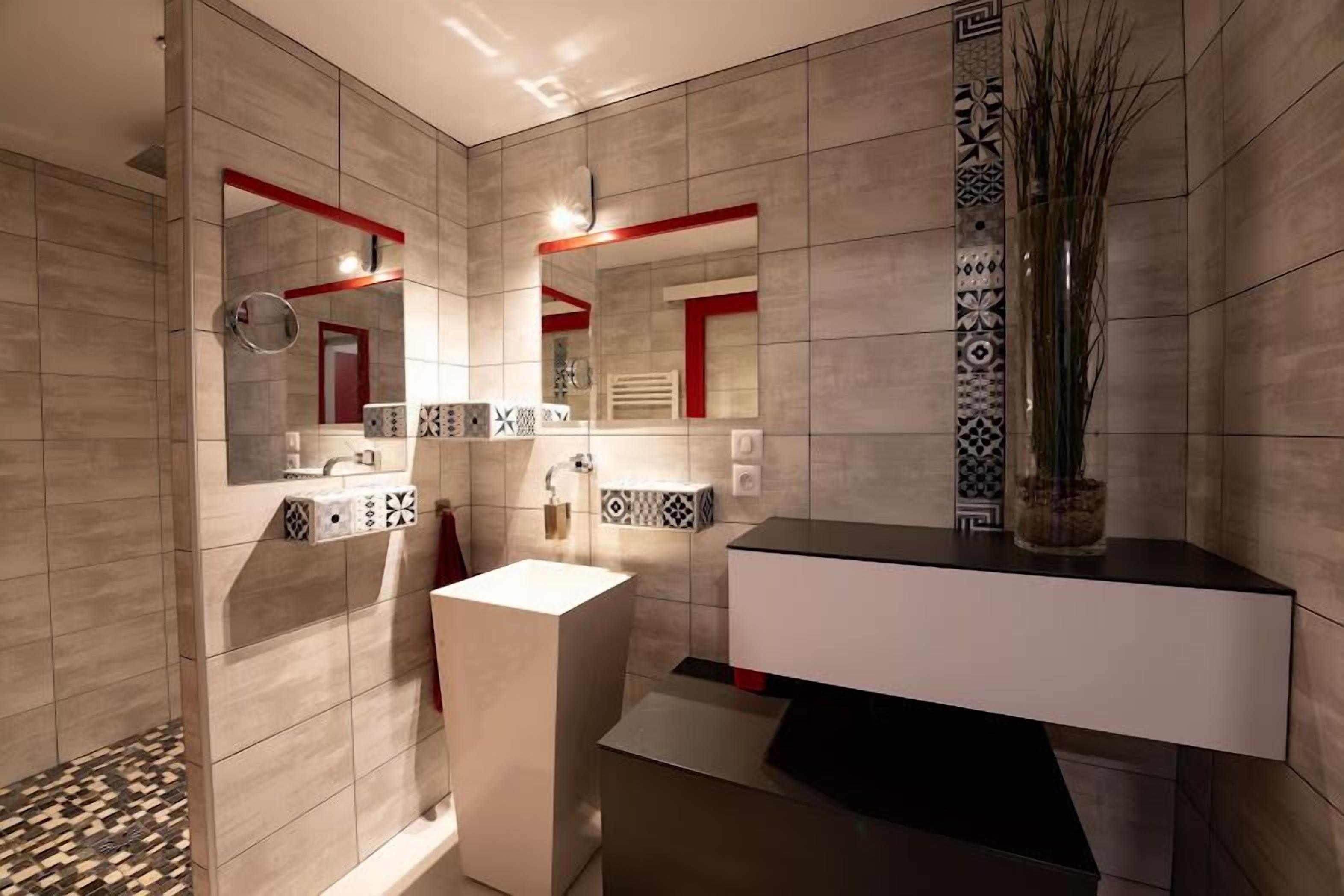 A modern bathroom with a large mirror, a white sink, and a black countertop.