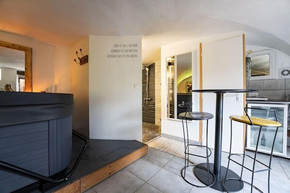A compact kitchen with a built-in stove, a small dining area with stools, and a wall-mounted mirror.