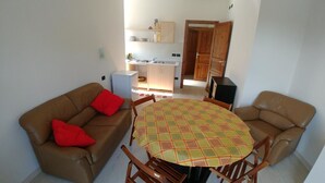 A living room with a round table, two brown leather sofas, and red cushions. - Agriturismo Bastià (Corio)