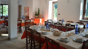 A dining area with multiple tables set for a meal, chairs, and a window providing a view of the outdoors. - Agriturismo Bastià (Corio)