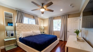 A bedroom with a large bed, a ceiling fan, a bedside table with a lamp, and a nightstand with a glass of water. - "Palm Estate" - Spacious 3 bed, 3 bath, 2 story single family home with pool (Hallandale Beach)