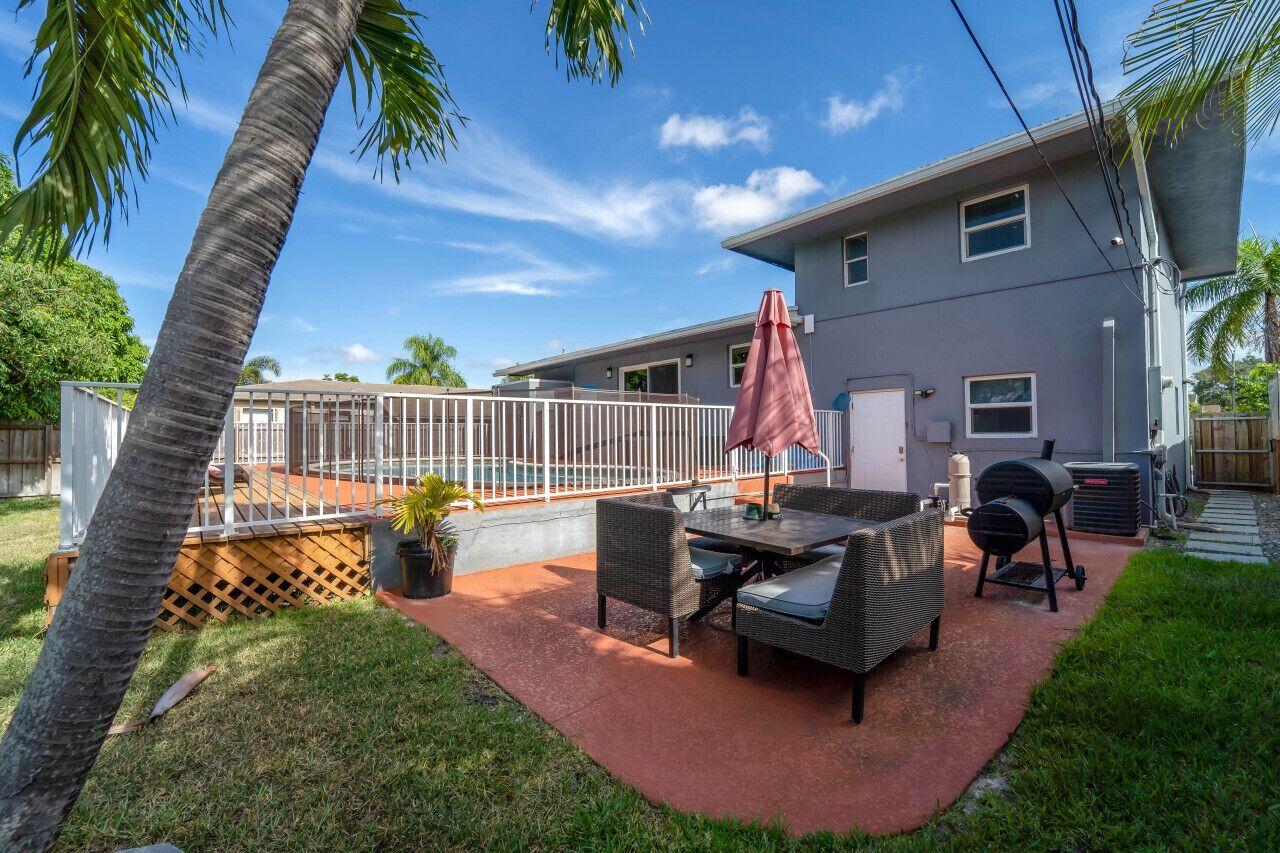 A backyard with a patio, outdoor furniture, a grill, and a pool.