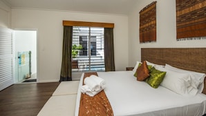 A hotel room with a large bed, a window with curtains, a wall-mounted artwork, and a door leading to a balcony. - Reflections Topaz Villa 3 (Picnic Bay)