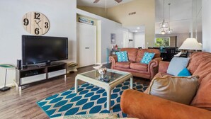 Ein Wohnzimmer mit Flachbildfernseher, Deckenventilator, Couchtisch und braunem Ledersofa.