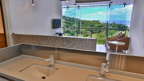 A modern bathroom with dual sinks, a large mirror, and a view of a lush landscape through large windows. - The Malinche Palace (Sardinal)