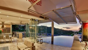A modern indoor area with a glass wall, seating, and a view of a pool and mountains. - The Malinche Palace (Sardinal)