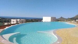 A large, clear swimming pool with a curved edge, surrounded by a paved deck. - Villa Cristina - Relax - Pool and Sea View (Castellammare del Golfo)