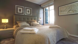 Une chambre à coucher moderne avec un grand lit, une table de chevet, une lampe et une fenêtre avec des stores.