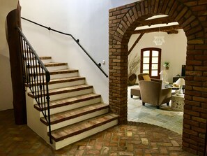 A staircase with a brick base and a wooden handrail leading to a living area with a brick archway. - Prestige Villas | EAST COAST | Villa with Infinity Pool & Stunning View (Corfu)