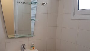 Een badkamer met een wit wastafel, een spiegel, een toilet en een douchehoek.