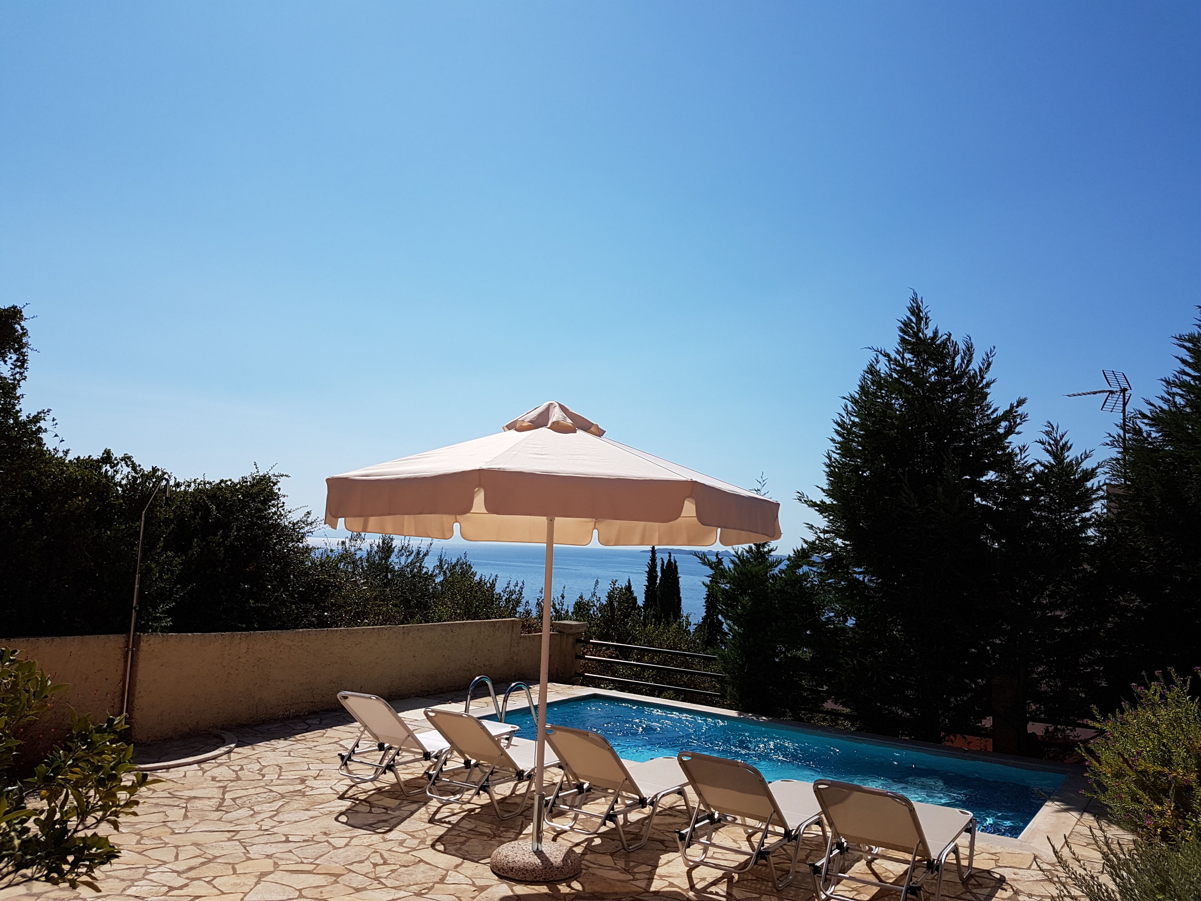 A swimming pool with lounge chairs and an umbrella.
