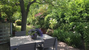 A garden patio with a table and chairs, surrounded by lush greenery and flowering plants. - Parkweg 21, Westkapelle (Westkapelle)