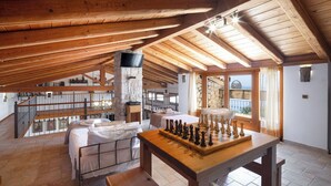 A spacious loft bedroom with a wooden ceiling, a large window, and a chessboard on the floor. - Prestige Villas  |  NISSAKI  |  5* Stone Olive Press, Large Pool with Sea Views (Corfu)