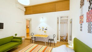 A room with a bed, a green sofa, a small table with a flower, and a desk with chairs. - Zip b&b in Florence (Florence)