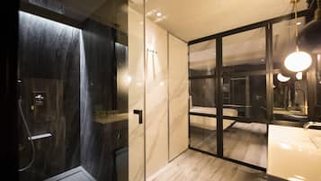 Une salle de bain moderne avec une douche à l’italienne en verre, un grand miroir et un plancher en bois.