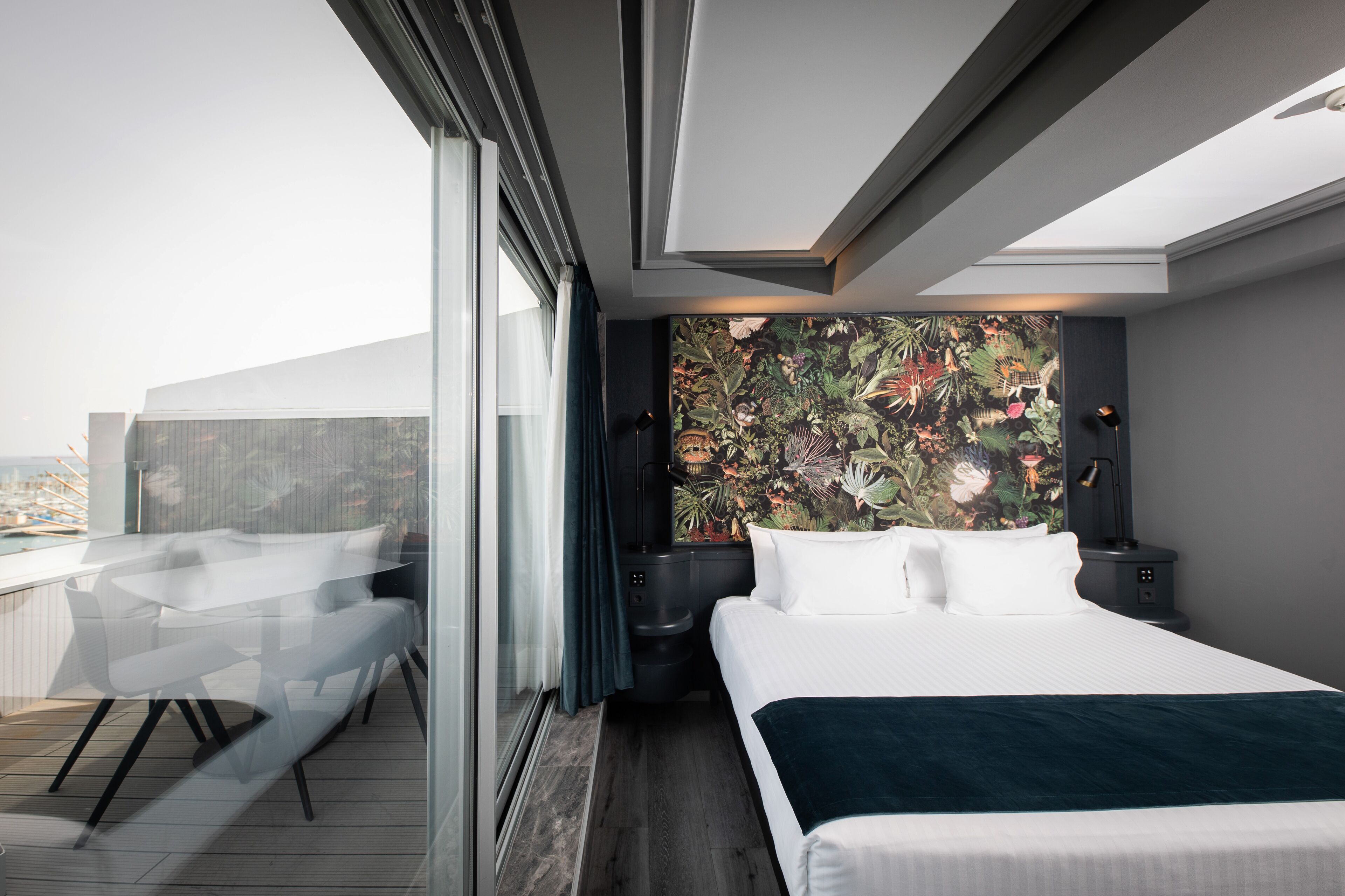 Una habitación de hotel moderna con una cama grande, un escritorio y vistas a la ciudad.