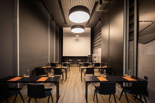 A conference room with a long table, chairs, a projector screen, and a large circular light fixture on the ceiling.