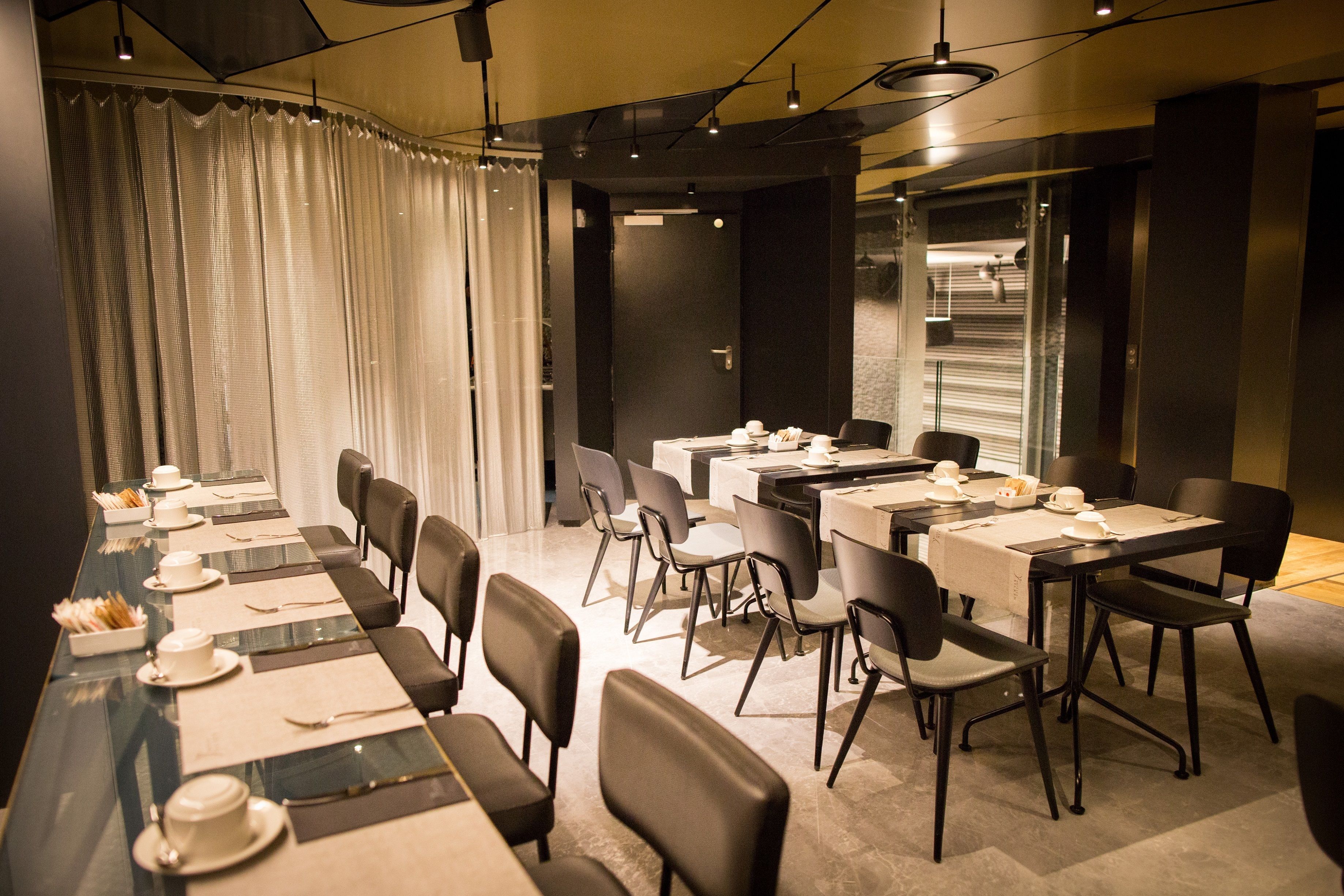 A conference room with multiple tables and chairs, equipped with nameplates and table settings.