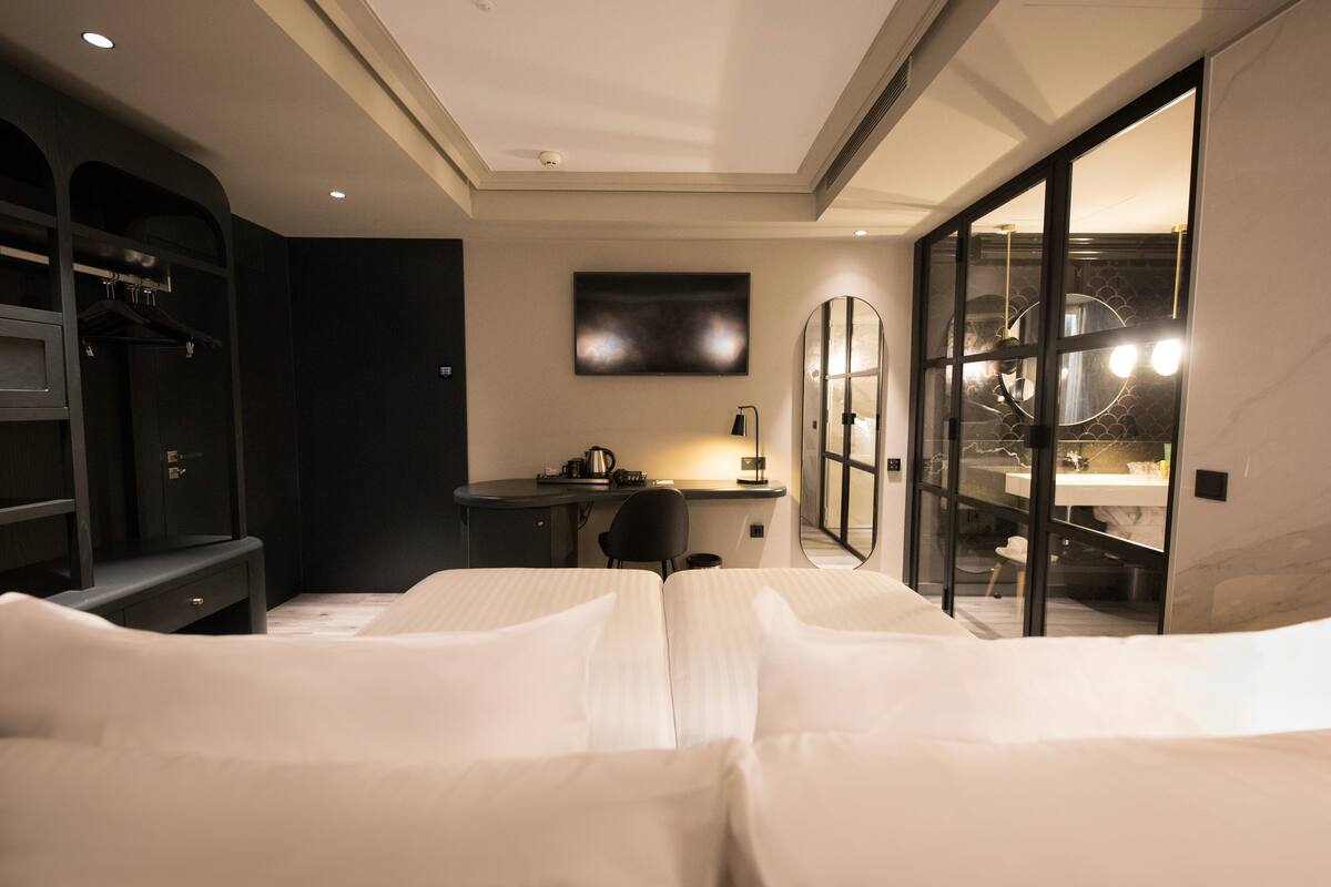 Ein Hotelzimmer mit Bett, Schreibtisch, Stuhl und einem großen Spiegel.