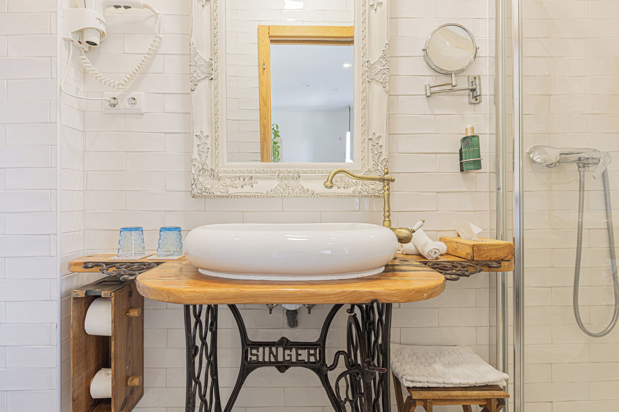 A bathroom with a white sink, a mirror with an ornate frame, a shower, and a towel rack.