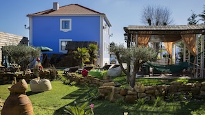 Une maison bleue avec un toit en tuiles, un mur en pierre et un hamac.