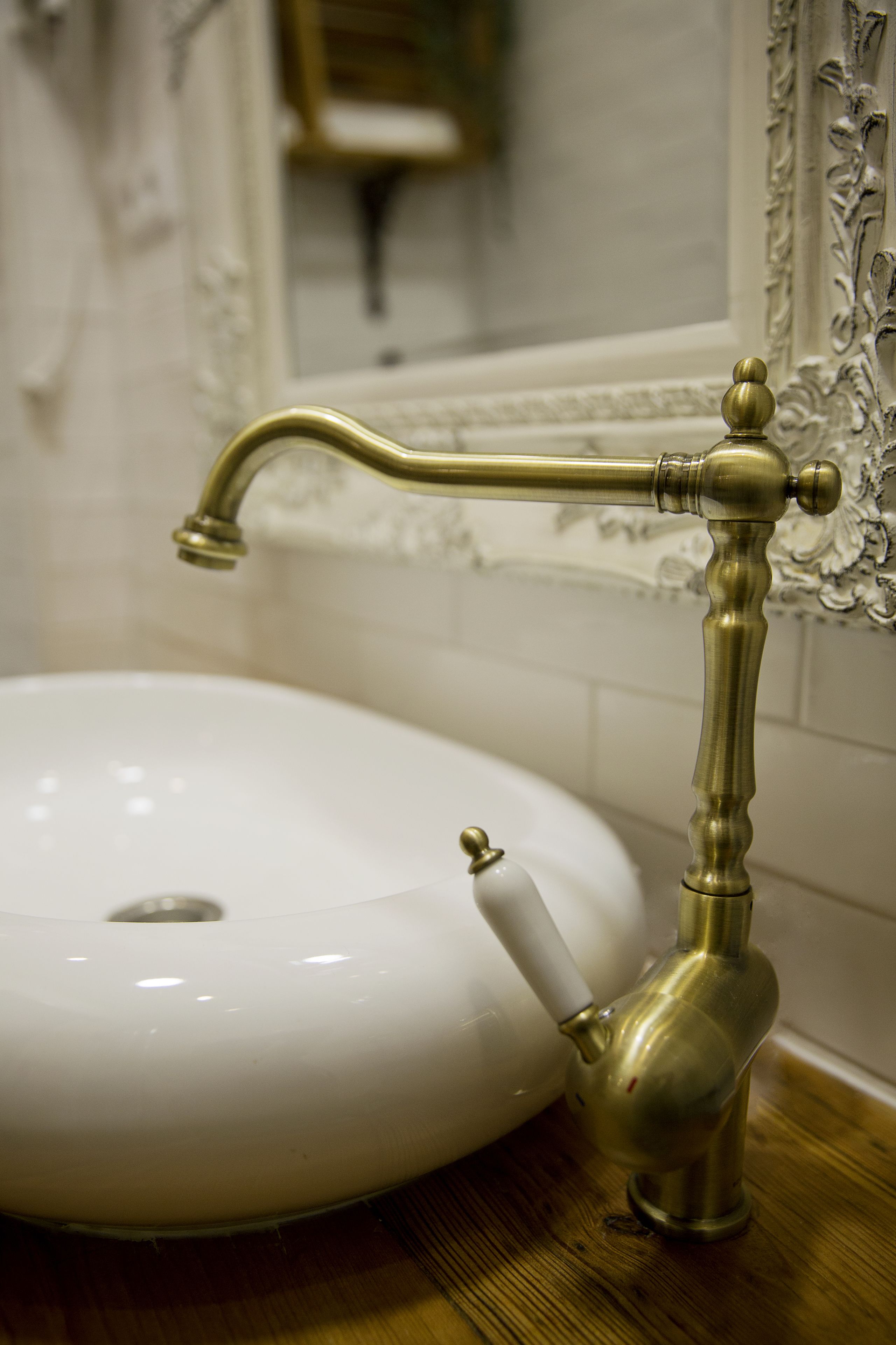 Un lavamanos de baño con un grifo de latón antiguo y una pileta de porcelana blanca.