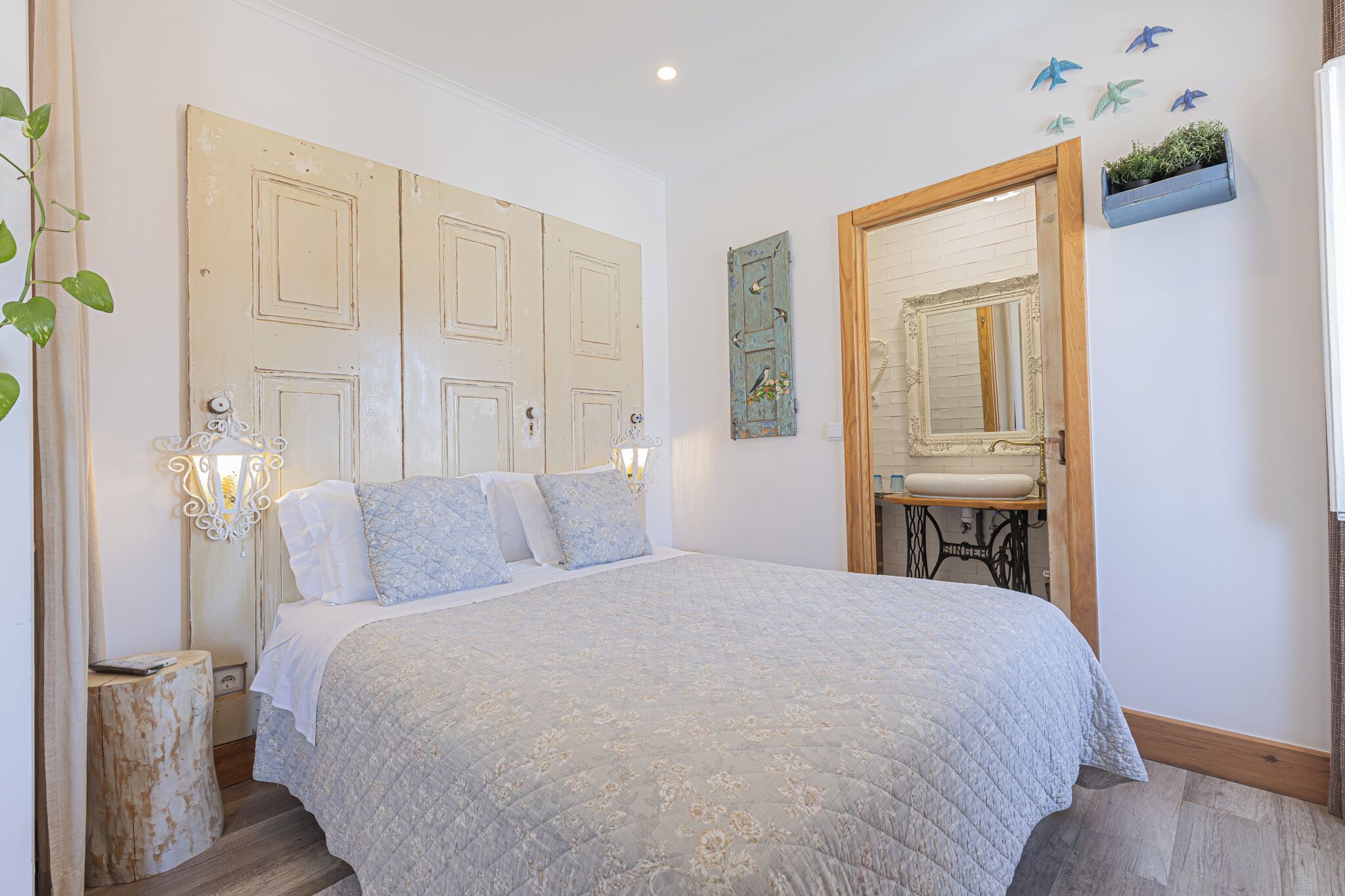 A bedroom with a large bed, a wooden door, a mirror, and a small sink.