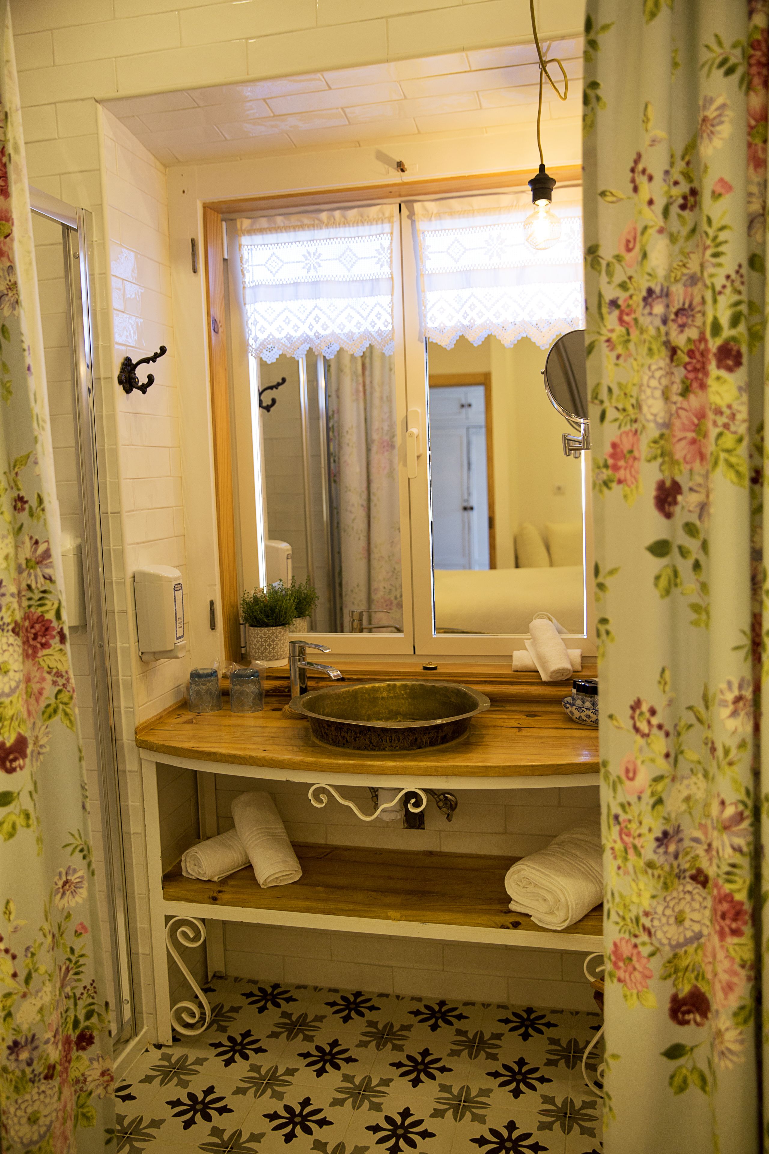 Un baño con tocador de madera, un espejo, un lavabo, un perchero para toallas y una zona de ducha.