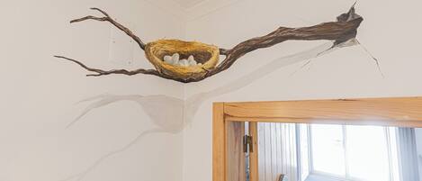 A room with a unique ceiling design featuring a branch with a nest.