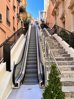 Un escalier mécanique intérieur mène à un escalier qui offre une vue dégagée sur les bâtiments environnants.