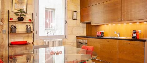 Une cuisine moderne avec des meubles en bois, une table à manger en verre et des chaises rouges.