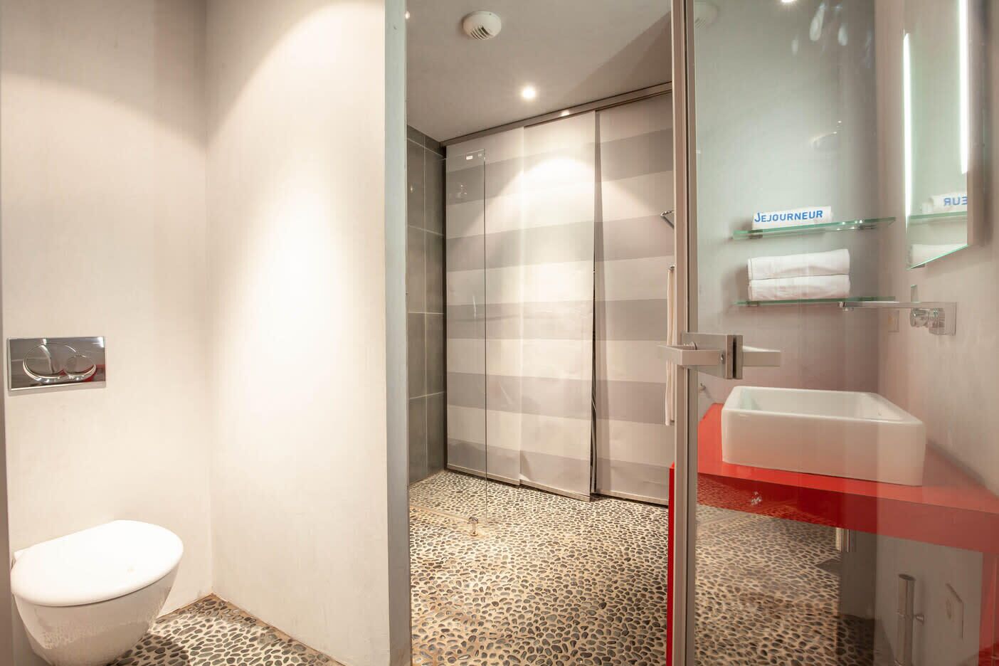 A modern bathroom with a toilet, shower, and glass-enclosed walk-in shower.
