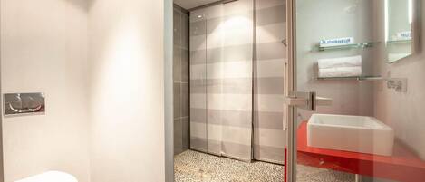 A modern bathroom with a toilet, shower, and glass-enclosed walk-in shower.