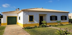 A single-story house with a tiled roof, a green door, and yellow trim.