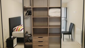 A bedroom with a bed, a wardrobe with multiple shelves, a chair, and a bedside table with a lamp. - Large chic and modern loft, industrial decor (Beausoleil)