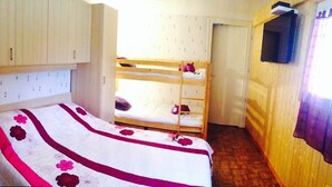 Habitación con literas, una cama individual, armario y ventana con cortinas.