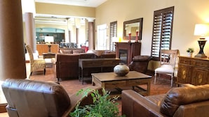 A spacious living area with leather sofas, a wooden coffee table, and a large vase. There is a dining area in the background with a wooden cabinet and a chair. - Suite in Orlando | Access to Shared Pool/Hot Tub (Orlando)