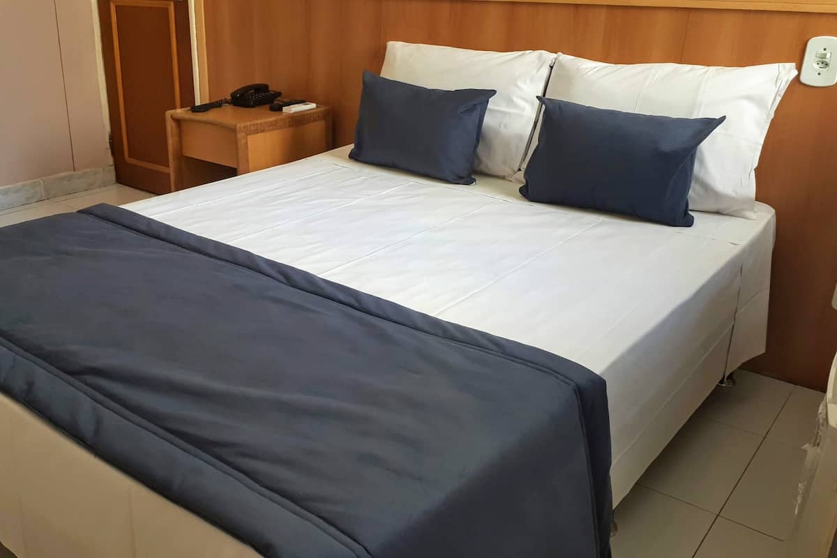 A hotel room with a bed, bedside table, and a telephone.